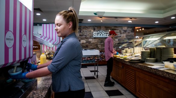 A staff member at Sizzler Campbelltown pulls soft serve for a table of customers.
