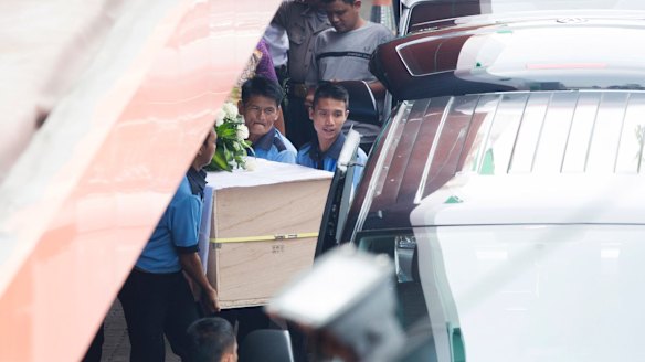 Workers at Abadi funeral home place one of the coffins into a hearse.