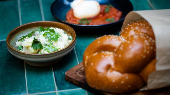 Glossy challah with dip and pickles.