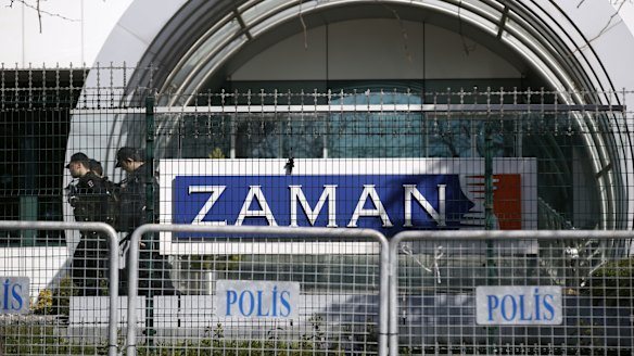 Riot police officers walk by the headquarters of <i>Zaman</i> newspaper in Istanbul after it was shut down.