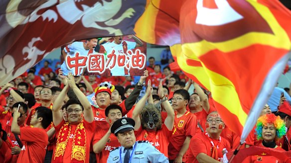 A policeman looks on as Chinese soccer fans cheer during the 2018 World Cup qualifying match between China and Iran in Shenyang, China, last week.
