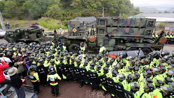 South Korean police protect a US military vehicle from protesters who oppose a plan to deploy the THAAD system against North Korean attack.