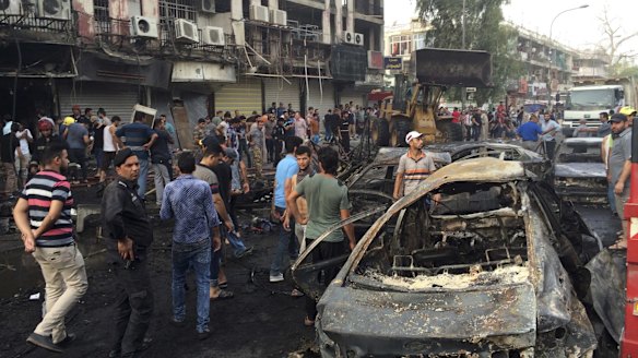 Iraqi security forces and civilians gather at the site after a car bomb exploded in a Baghdad commercial district.