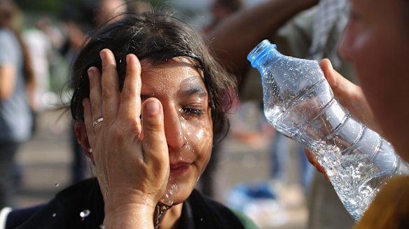 A migrant girl is overcome by pepper spray and tear gas after Hungarian police repelled an attempt by migrants to break the border post gate.