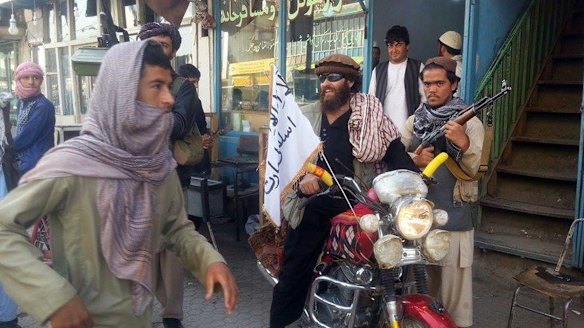 A Taliban fighter sits on his motorcycle adorned with a Taliban flag in Kunduz.