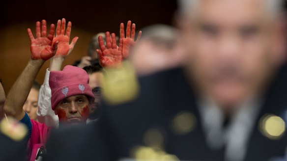 A demonstrator from Code Pink raises his hands as General John Campbell, commander of US forces in Afghanistan, right, speaks during a Senate committee hearing in Washington earlier this month.