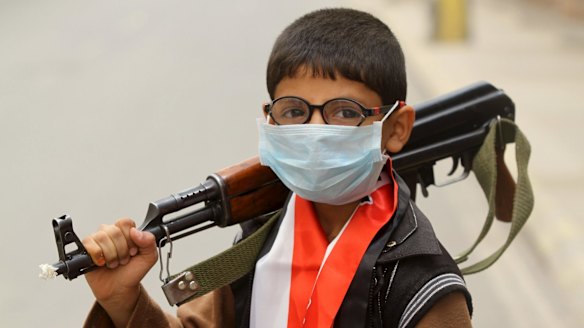 A boy holds a machine gun in Sanaa, Yemen, ahead of a sandstorm.