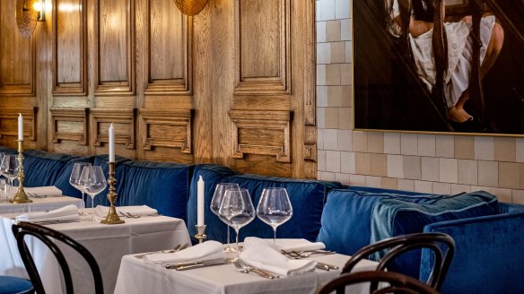 The dining room features royal blue velvet, white tablecloths, a fireplace and timber panels along one wall, which were sourced from a chateau outside Paris