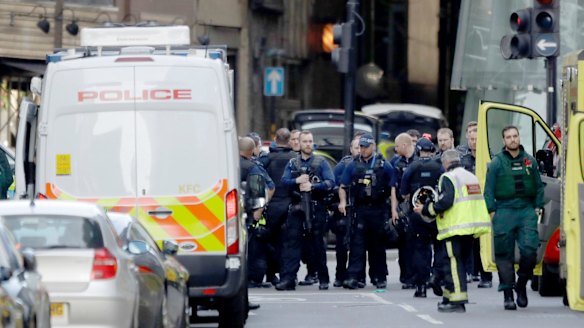 Armed British police officers walk within a cordoned off area after the attack. 