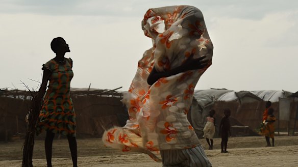 A woman walks along a road as the rains come inside the United Nations' Bentiu Protection of Civilians site, home to over 100,000 people who have fled violence and food insecurity. 