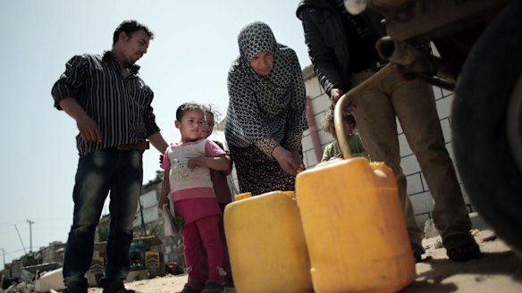 A Palestinian family fill plastic containers with drinking water they bought from a vendor in Khan Younis refugee camp, in the southern Gaza Strip.  