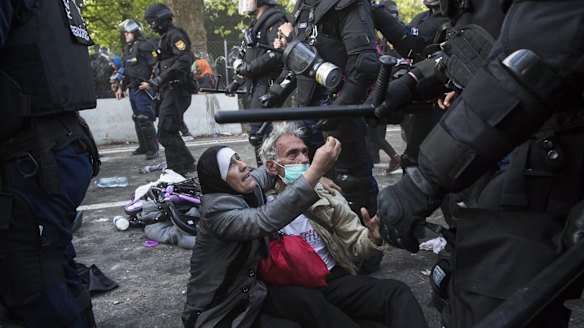 A woman pleads with police after her husband was cut on the head as migrants clashed with police on the Hungarian border with Serbia.