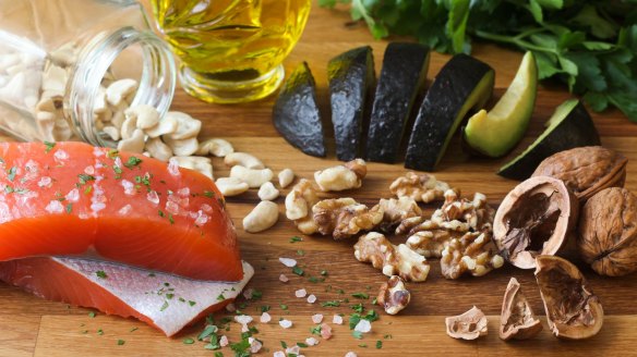 Salmon seasoned with salt, cashews, walnuts, sliced avocado, and olive oil, garnished with parsley.