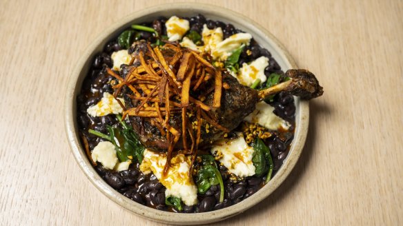 Confit duck with black beans, spinach and clumps of Oaxaca cheese.
