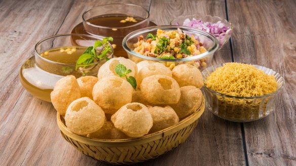 Pani puri, a common Indian street snack, consists of crisp, hollow breads filled with flavoured water and spicy vegetables.