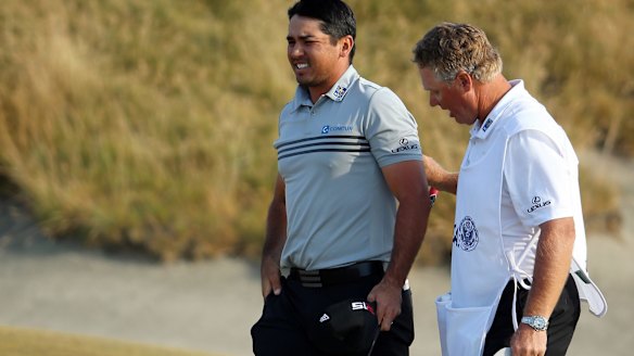 Jason Day of Australia walks off the 18th green with his caddie Colin Swatton after shooting a two-under par 68 during the third round of the US Open Championship.