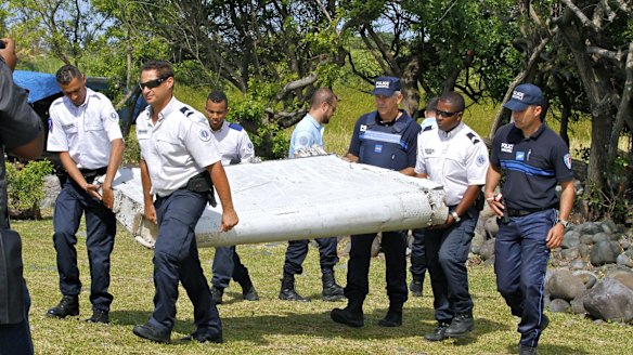 French police officers carry the piece of debris from a plane in Saint-Andre, Reunion Island.