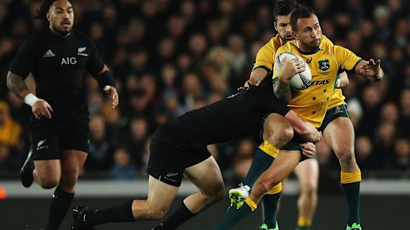 Hammered: Quade Cooper is hit hard on Saturday night.