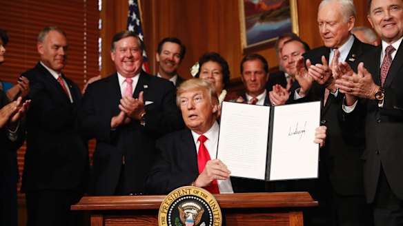 President Donald Trump holds up the signed executive order in Washington on Wednesday.