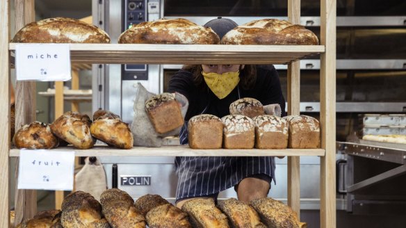 Jamie Goodin filling shelves with rustic miche and fruit loaves.