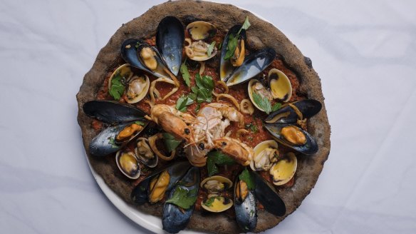 The grey, squid ink-infused base of a pizza Amalfitana is scattered with lightly cooked seafood.