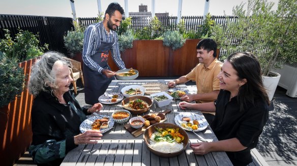 Lakshay Gumber (standing) serves a Middle Eastern feast to friends an neighbours on the rooftop of his Brunswick apartment block. 