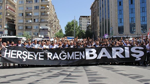 People holding a banner that reads ''Peace despite everything'' march to the site of the attack.