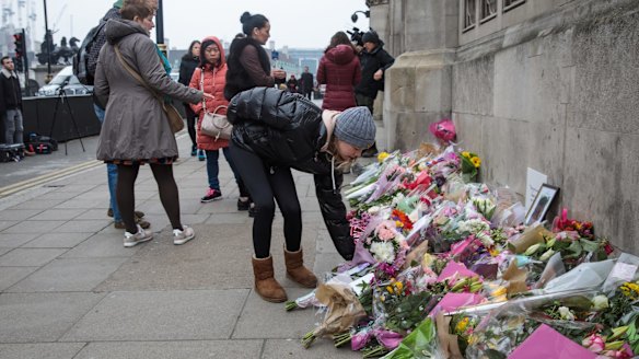 A young woman lays flowers outside the Houses of Parliament following Wednesday's attack on Westminster.