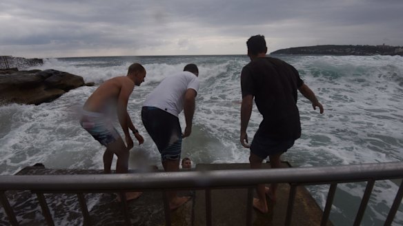 Lifeguards and surfers battled powerful waves close to rocks to pull the man out.