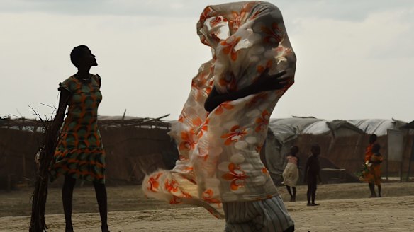 A woman walks along a road as the rains come inside the United Nations' Bentiu Protection of Civilians site, home to over 100,000 people who have fled violence and food insecurity. 