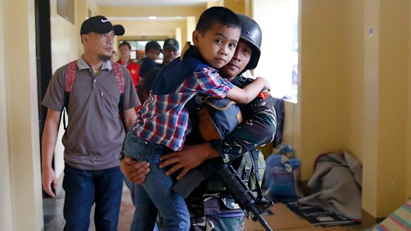 A government solider carries a boy after he was rescued from the site of the fighting between the Philippine troops and Muslim militants in Marawi city on Wednesday.