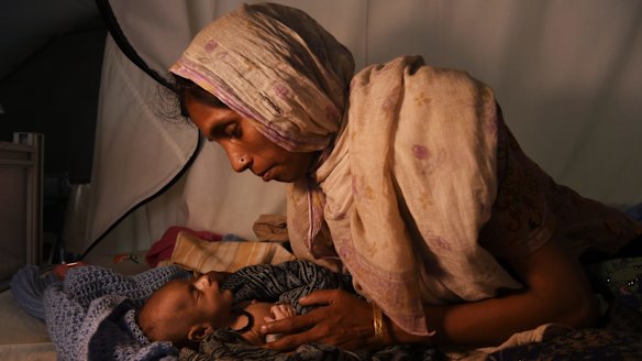 Rohingya woman Laila Begum holds her son Mohammed Ifran's hand as he receives treatment at the Red Cross Field Hospital in Kutupalong refugee camp.
