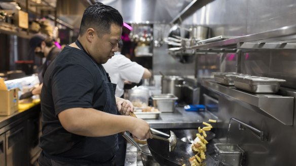 Chef Brendan Fong wok-fries pasta in Parramatta restaurant kitchen. 
