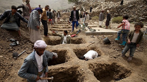 People dig graves for the victims of an air strike in Okash village near Sanaa on Saturday.