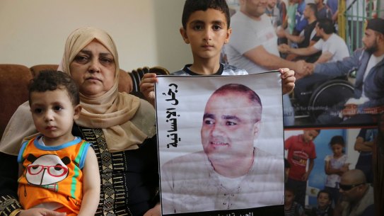 Amal el-Halabi holds her grandson Fares, 18 months old, while her grandson Amro, 7, holds a picture of his father Mohammed el-Halabi, World Vision's Gaza operations manager, who Israel accuses of diverting funds to Hamas. The alleged figures exceed the total World Vision budget for Gaza.