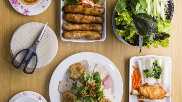 A spread of spring rolls, sugar cane prawns, fresh rice pastry and accompanying fresh herbs and dipping sauce. 