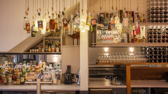 Bottles swing above the bar at Rosenbaum & Fuller, Bondi.