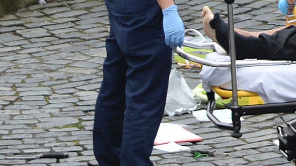 A man is treated by emergency services, as a knife lays on the floor, outside the Houses of Parliament London on Wednesday.