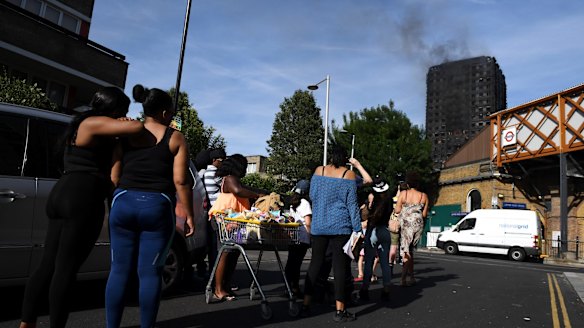 People look on from Latimer Road Station at the smoking 24-storey Grenfell Tower block.