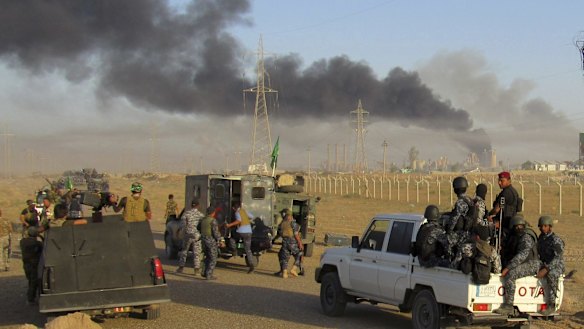 Smoke rises from Islamic State positions after an air strike by US-led coalition warplanes in Fallujah, as Iraqi security forces and allied Shiite and Sunni militias look on.