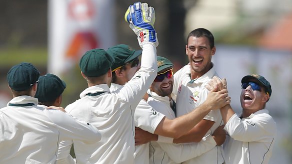 Australia's Mitchell Starc celebrates with teammates after taking a wicket with the first ball.