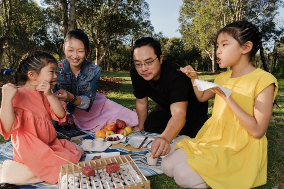 Firepop owners Alina Van and Raymond Hau charcoal grill with their daughters Arielle, 4, and Ariana, 9, at Sydney Park in Alexandria. 