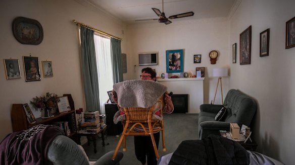 Glenys moves furniture out of the living room.