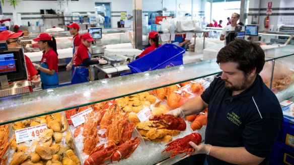 Sydney Fish Market guide Alex Stollznow holds a selection of fresh-cooked Australian lobster.