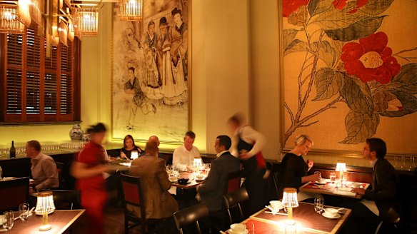 The golden-hued dining room is lined with elegant Chinese prints.
