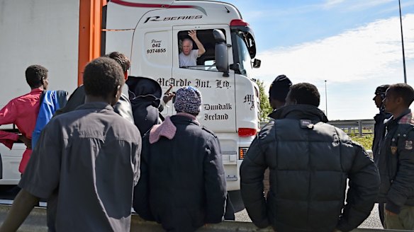 A truck driver on Thursday gestures at migrants as they try and board trucks bound for the United Kingdom in Calais, France. 