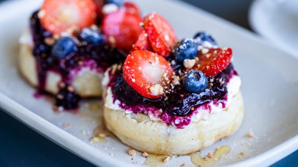 Golden sourdough crumpets with stewed fruit, strawberry slices, ricotta, honey and nuts. 