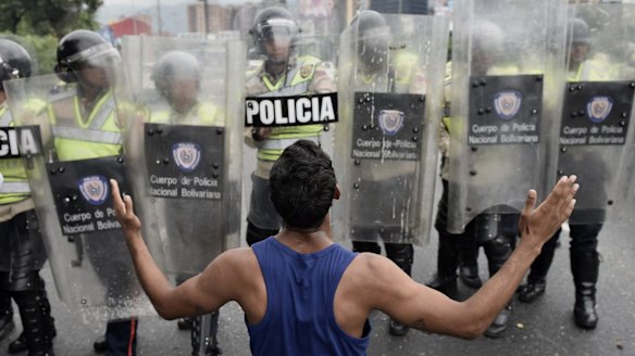 A protester gestures in front of police during an opposition march in Caracas on May 11.