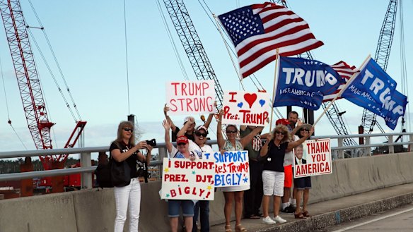 Supporters of US President Donald Trump stand on the bridge to his Mar-a-Lago estate in Florida, as his motorcade passes on Saturday.