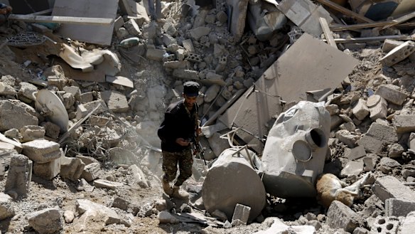A police trooper walks through a crater left by an air strike on houses near Sanaa Airport.